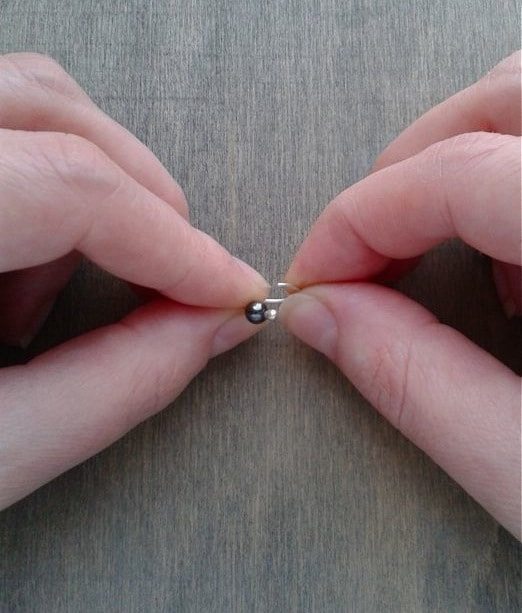 The gap in the hoop is shown open. The two ends are held by different hands between thumb ad index finger and they are moved in different directions turning the hoop from a circle to an arc of an helix 